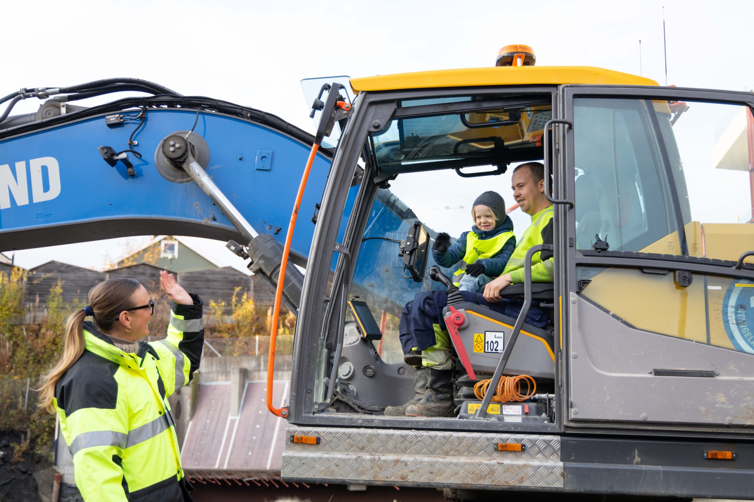 en liten gutt som sitter i en stor gravemaskin og vinker